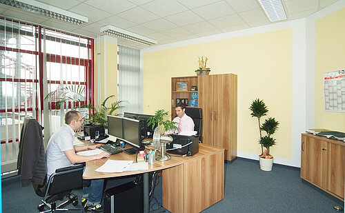 Büro mit zwei Männern, Schreibtischen und Computern