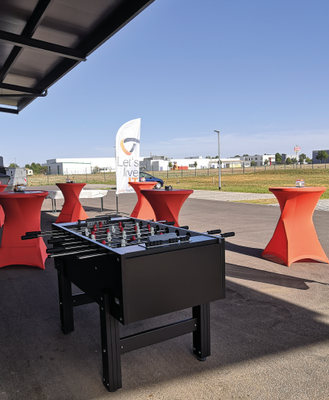 Exterior shot in front of the warehouse with bar tables & a foosball table
