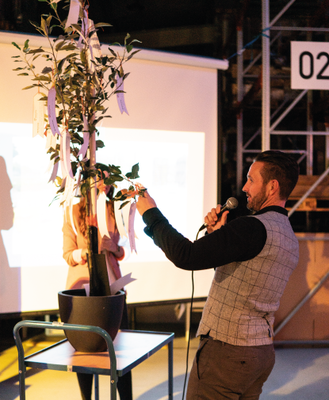 Frank Niemann nimmt als Einweihungsgeschenk der Cybertrading Mitarbeiter einen Apfelbaum mit Zukunftswünschen entgegen