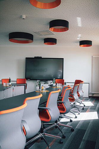 meeting room with desks, chairs and a bis screen on the wall