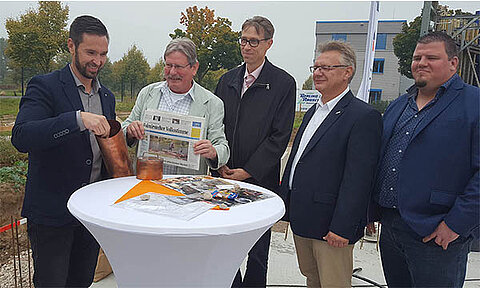 Frank Niemann und Bürgermeister der Gemeinde Barleben füllen eine Zeitkapsel
