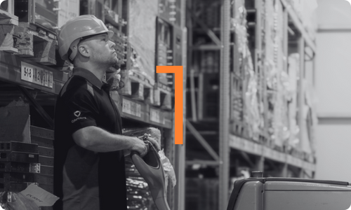 Mitarbeiter steht im Lager mit einem Stapler