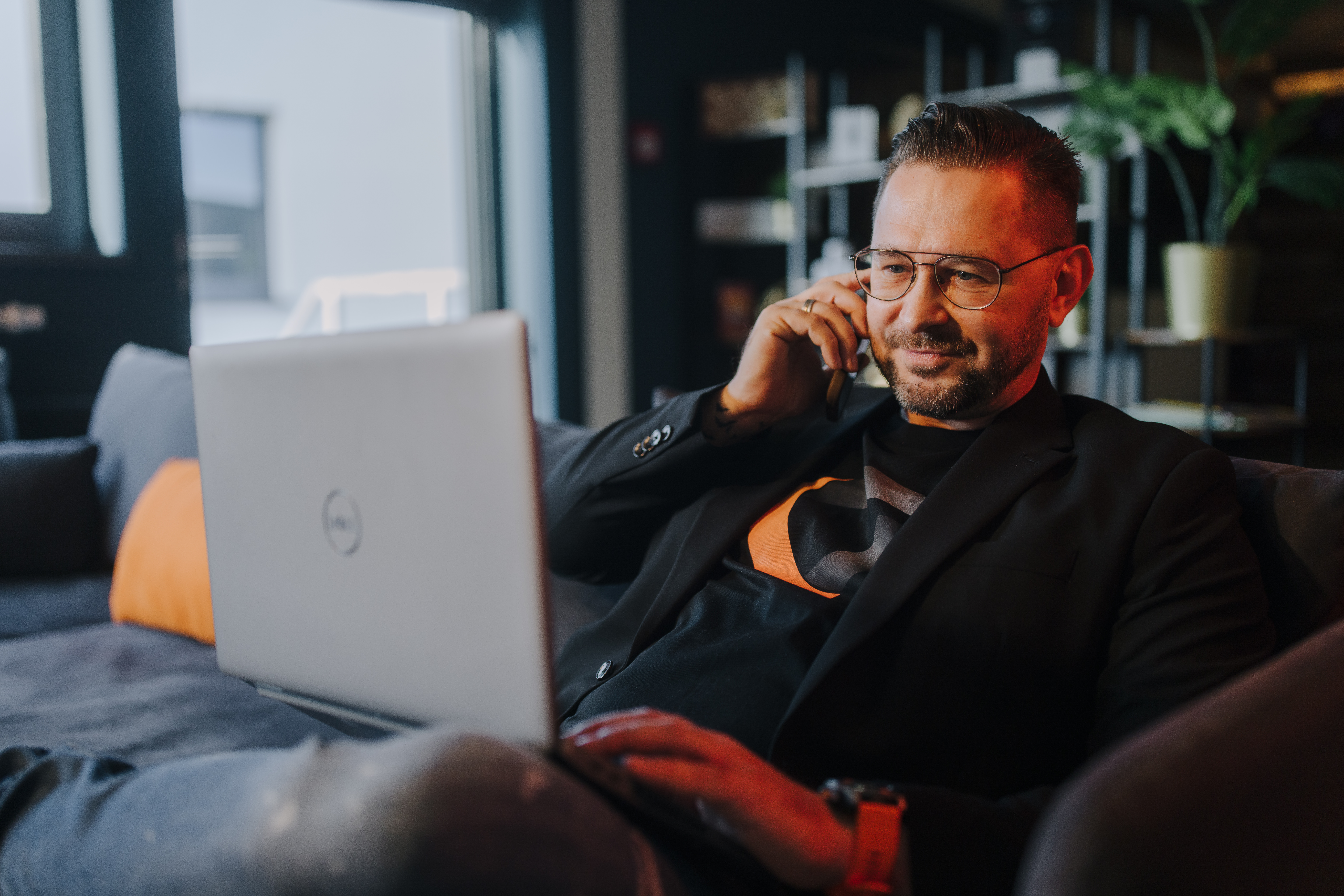 Sales manager with phone and laptop on the couch