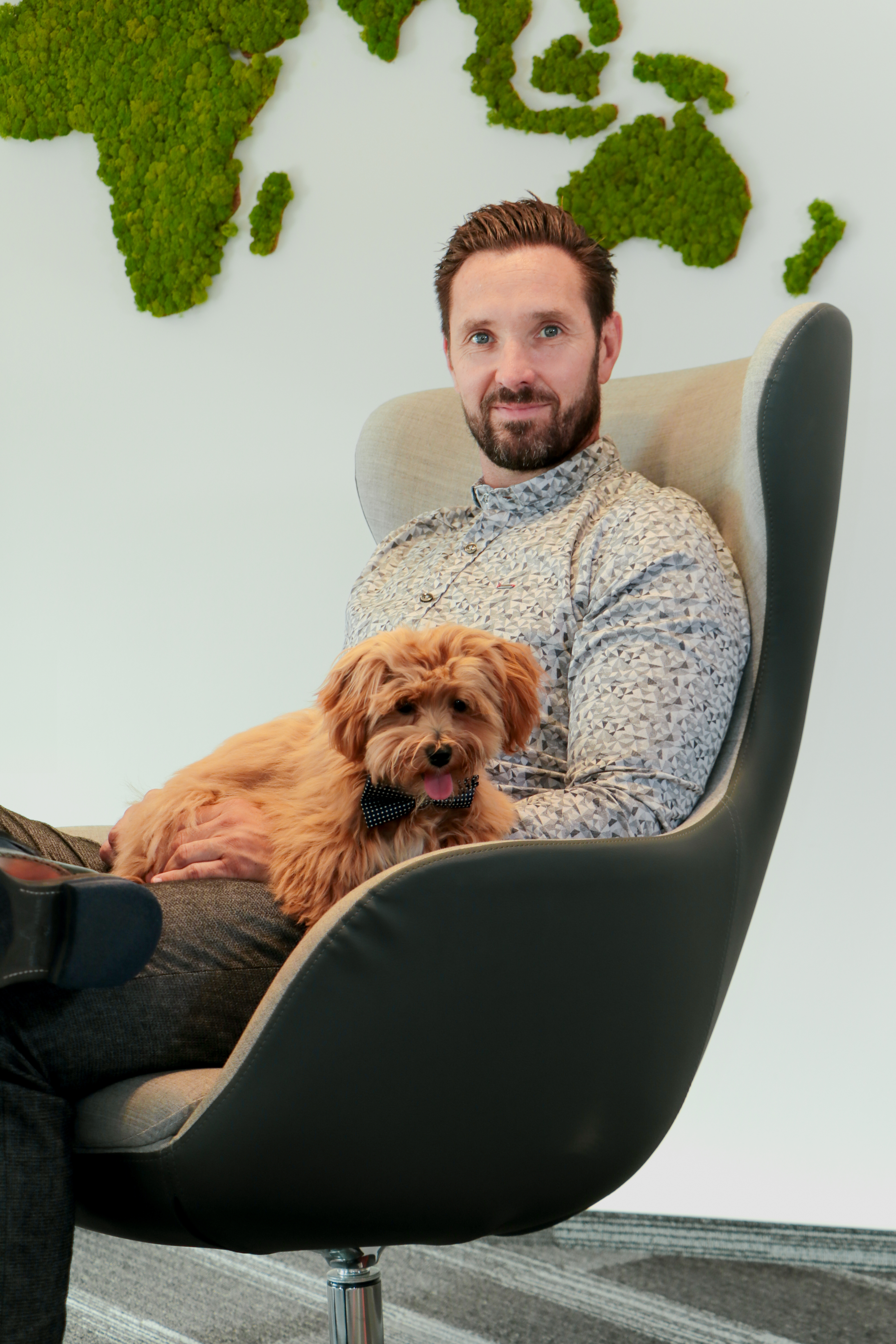 CEO Frank Niemann mit seinem Hund sitzend auf einem Bürostuhl